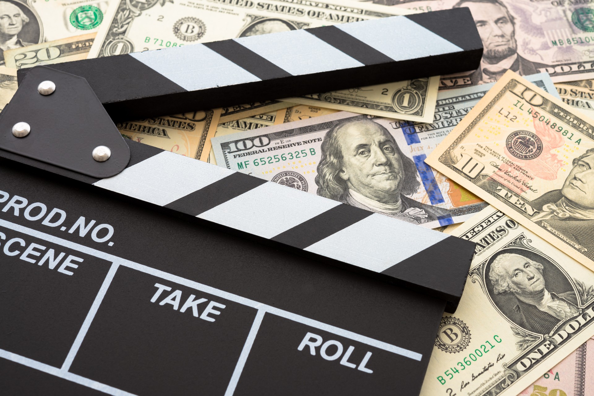 Cinema clapperboard on US dollars banknote bill background.